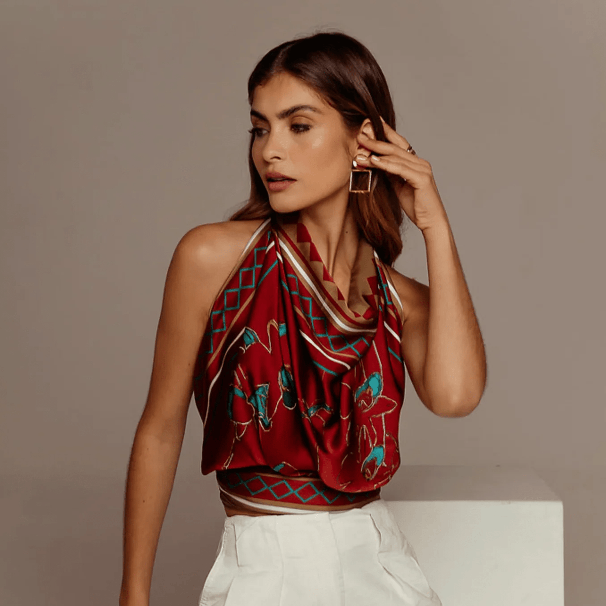 Woman wearing red floral silk halter top and white trousers, sustainable luxury fashion