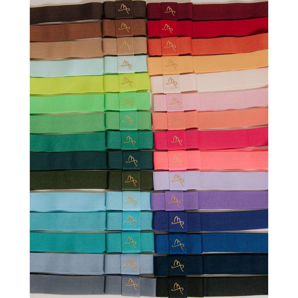 Assorted colorful fabric hatbands arranged in rows, each with a gold embroidered logo.