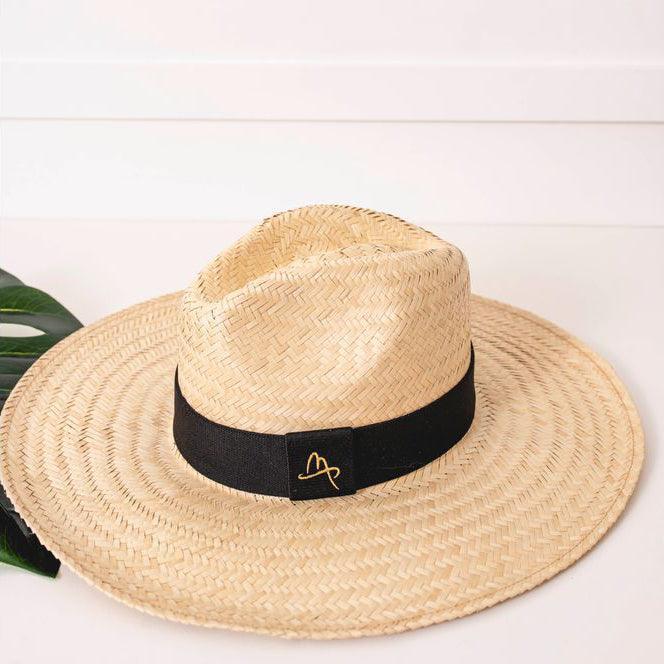 Large brim Panama-style carnauba straw hat with black band on white background