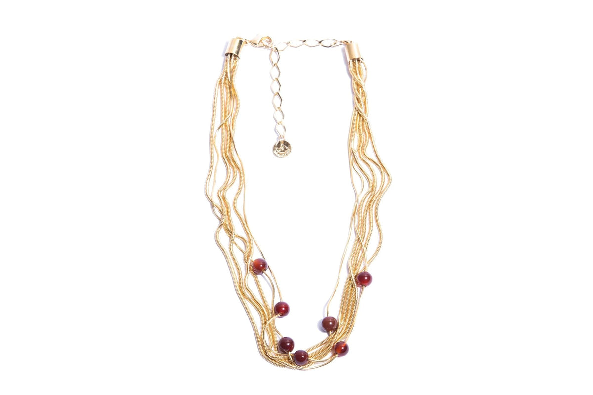 Gold multi-strand necklace with red beads on white background