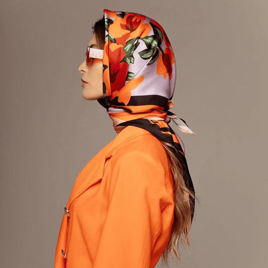 Woman in an orange coat wearing a By Femina silk scarf as a headscarf, autumn styling from Lachesis London