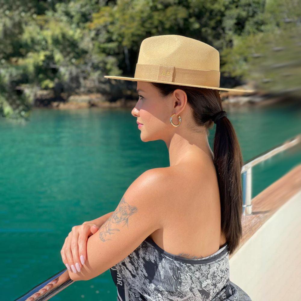 Woman in a beige Carnaúba straw Panama hat on a boat — handcrafted by Malu Pires for Lachesis London
