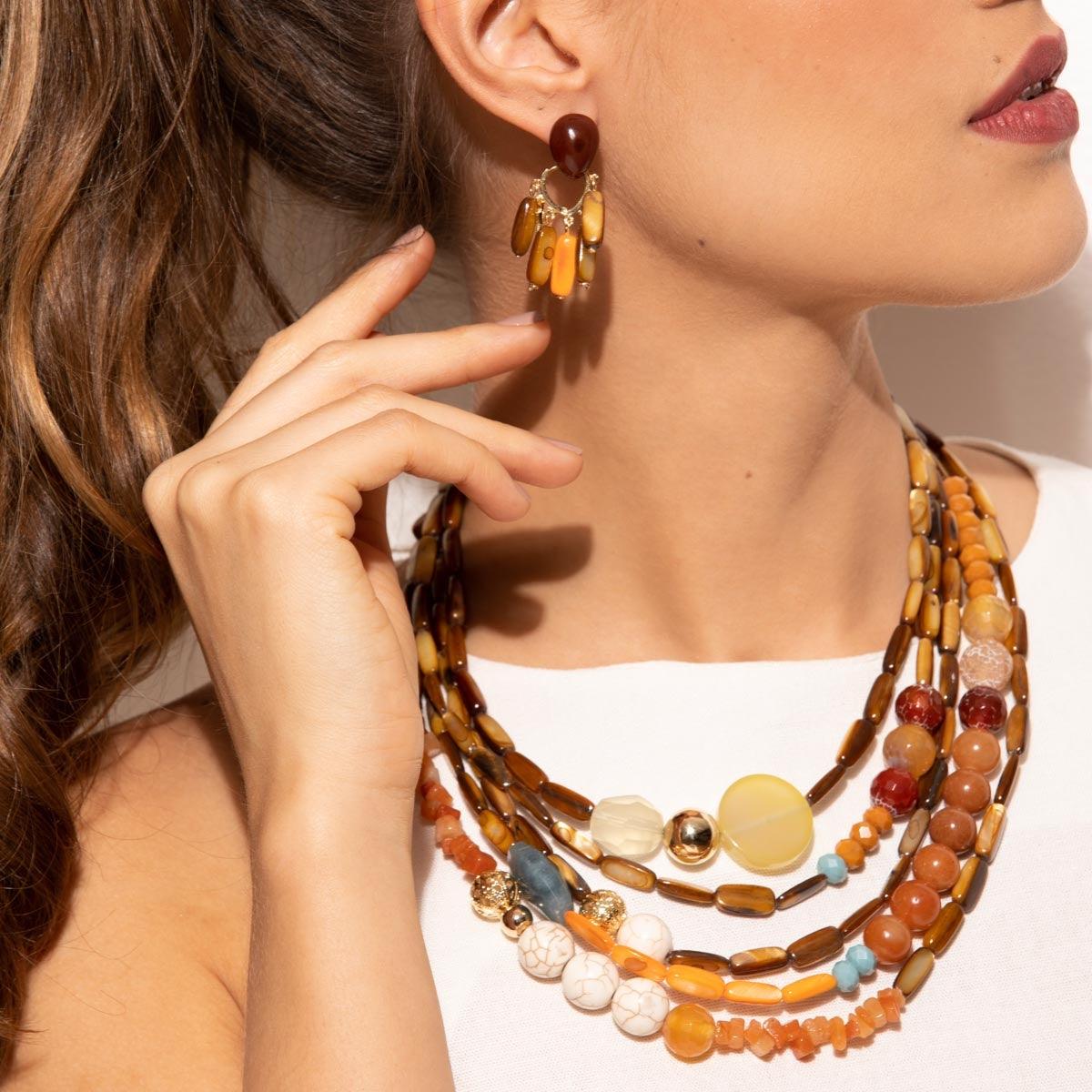 Model wearing dropped earrings. The festival earrings containing a mix of gemstones, pearls and agate are suitable only for pierced ears