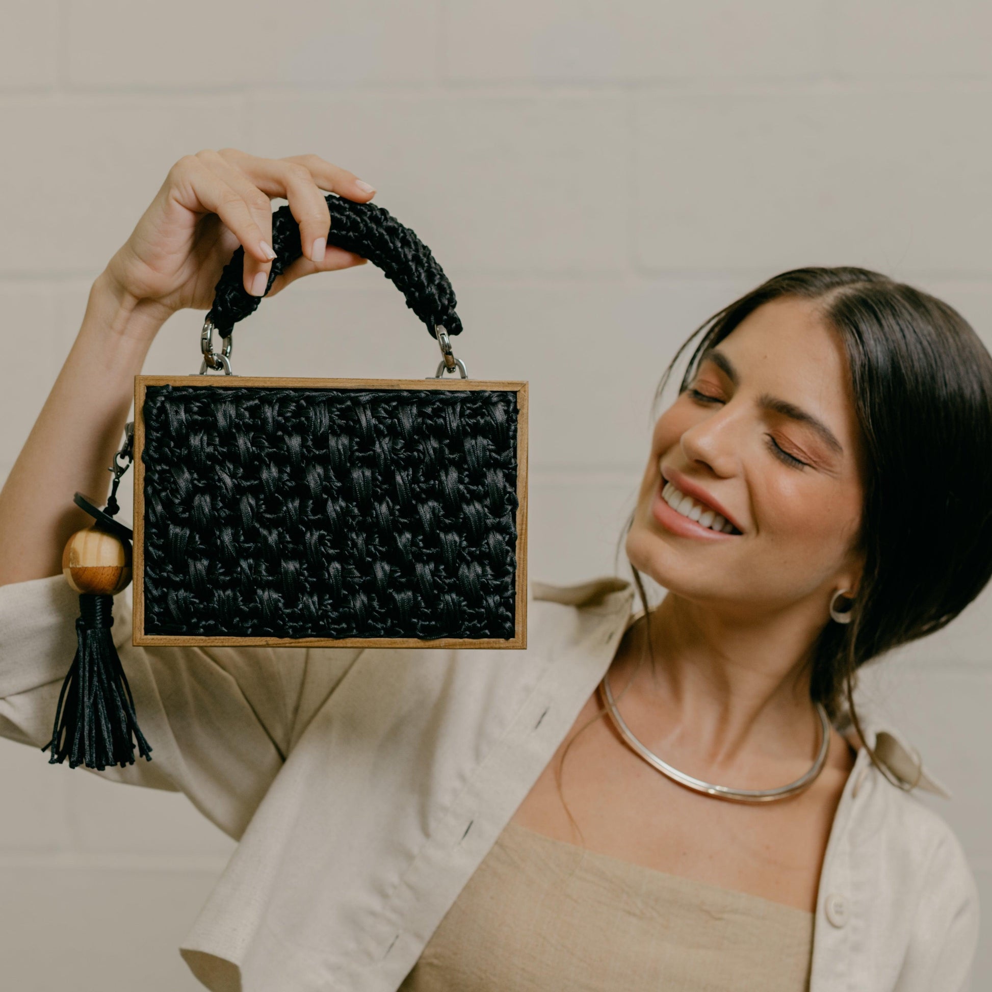 Model holding up the Revela with one hand. Rectangular shaped handbag with artisan satin crochet pattern.