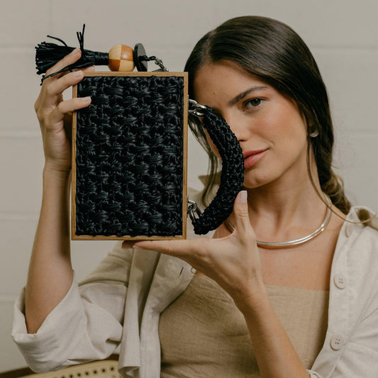 Model holding the Revela handbag on its side showing its rectangular shape and elegant design
